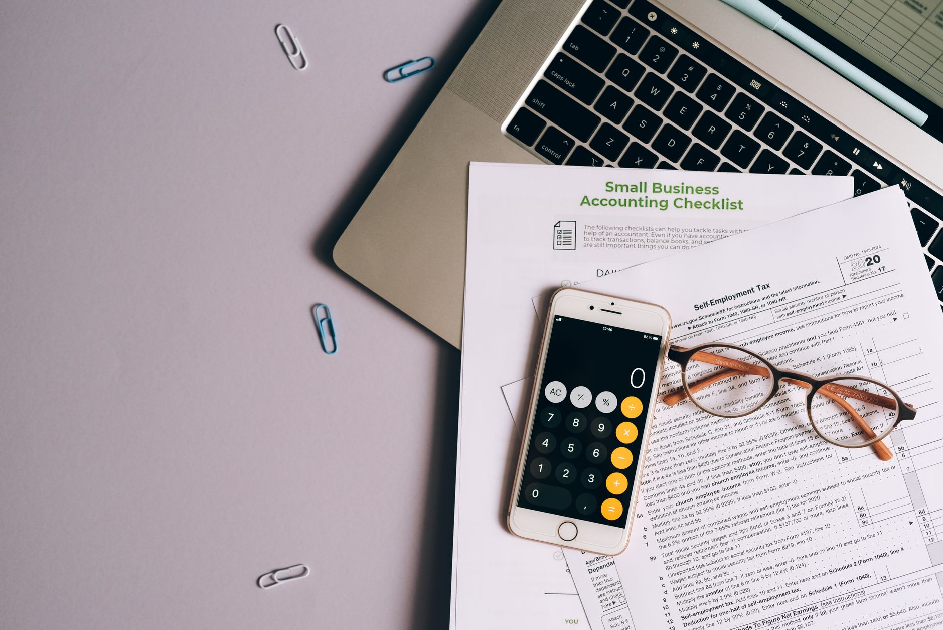 Nature morte d'outils de comptabilité pour petite entreprise : formulaire fiscal, téléphone et lunettes sur un bureau.