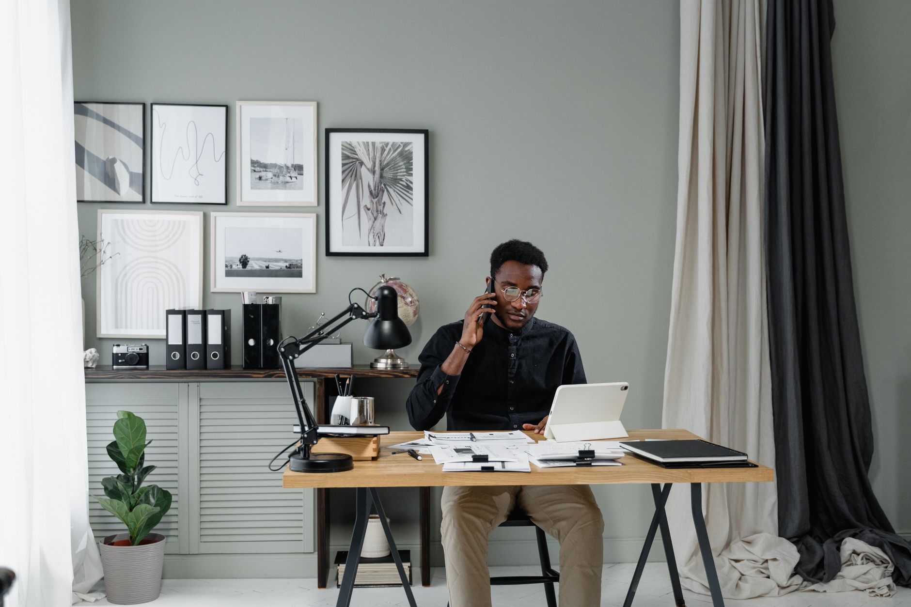 Homme d'affaires au téléphone dans un bureau élégant, avec tablette et documents.