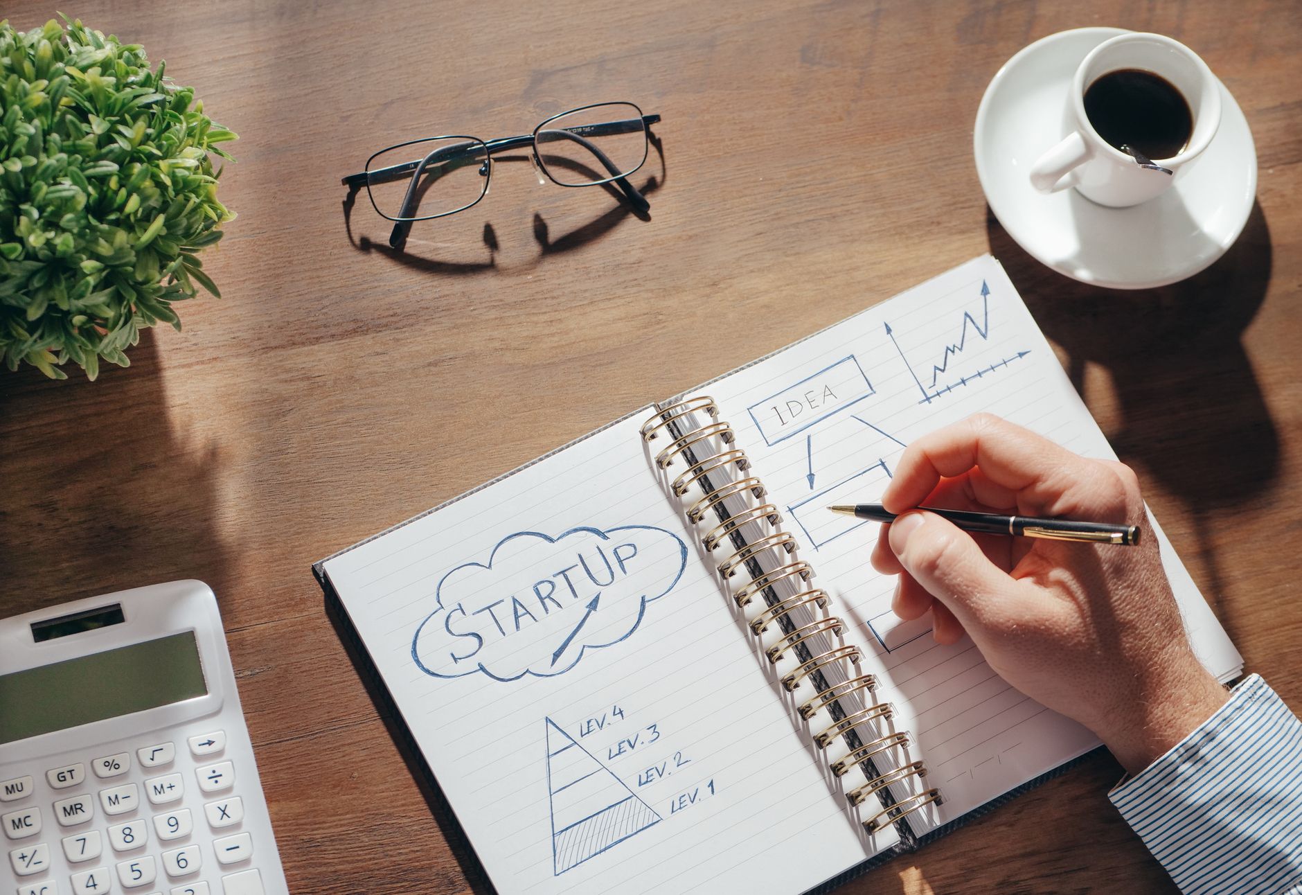 Espace de travail créatif avec un carnet de planification, des lunettes et une tasse de café.