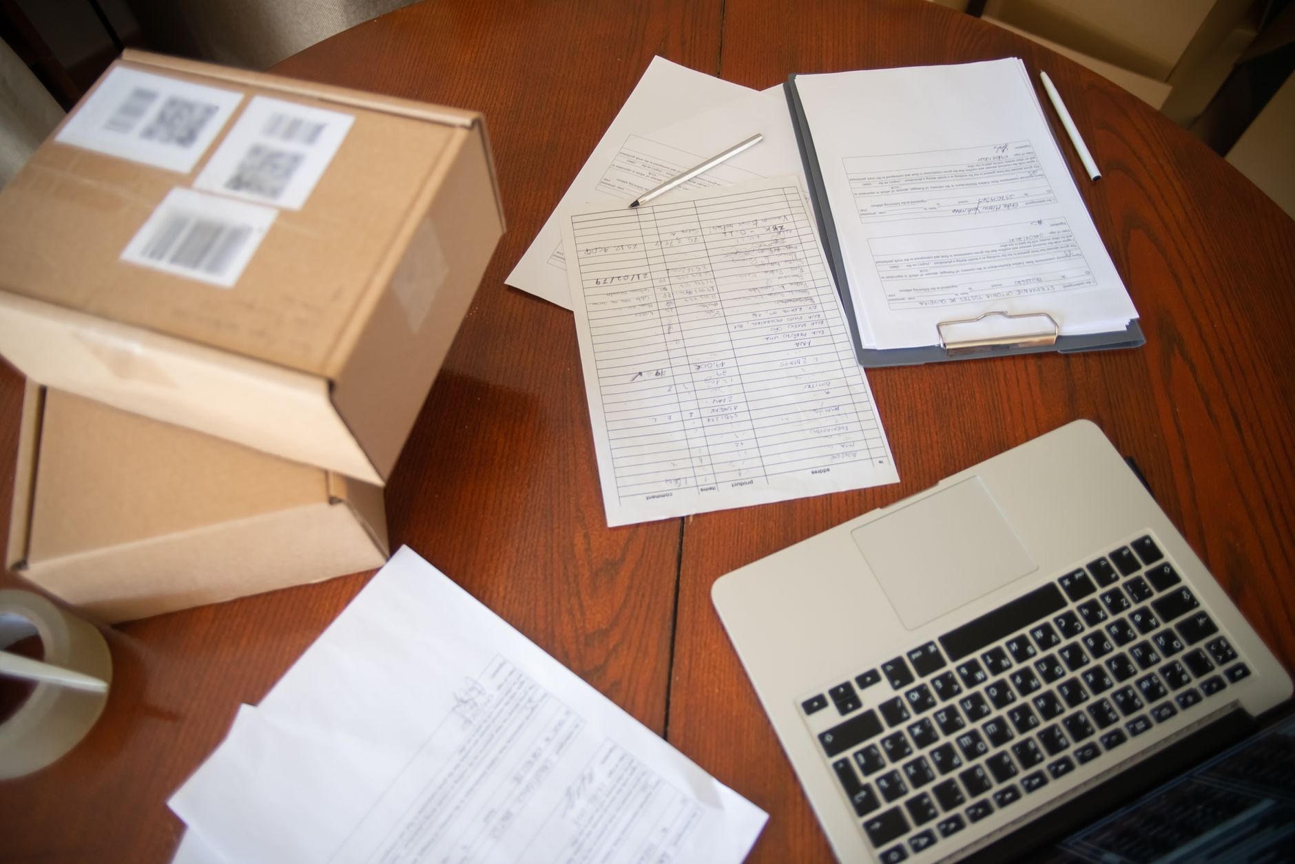 Nature morte d'un espace de travail avec ordinateur portable, documents et cartons pour la vente en ligne.
