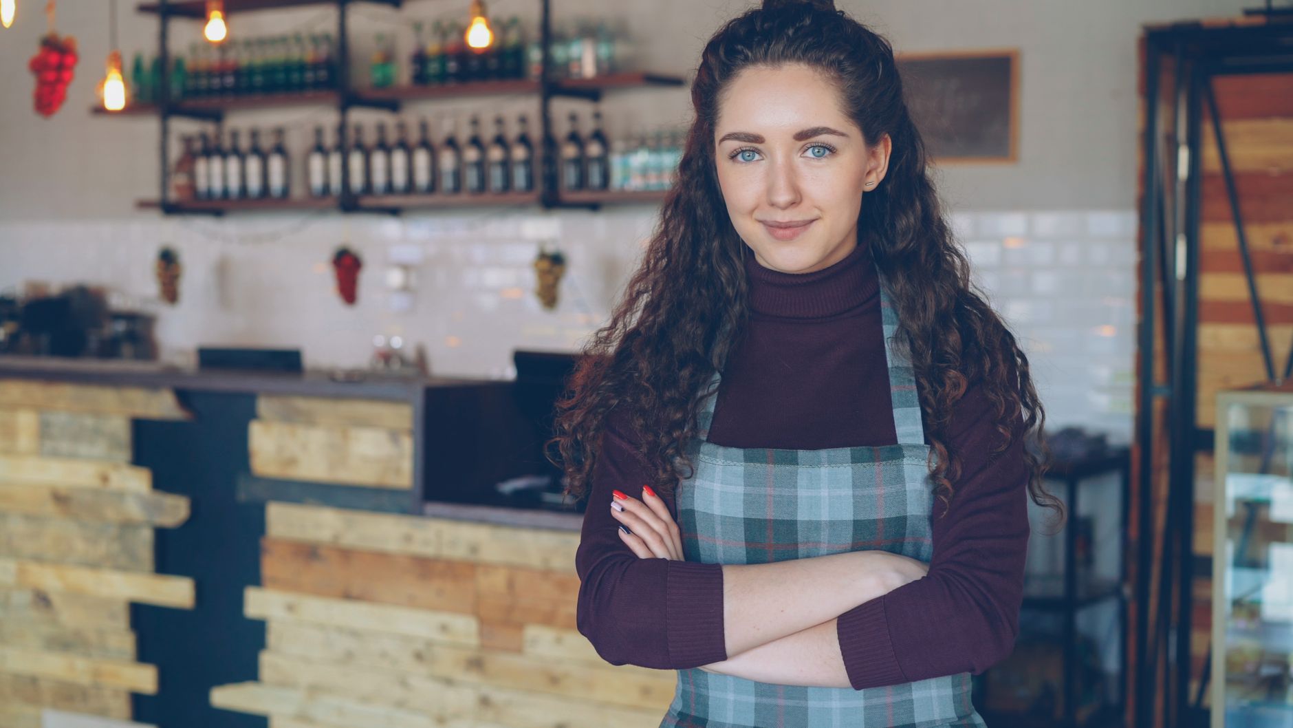 Propriétaire de café confiant, bras croisés, dans une boutique chaleureuse et rustique.